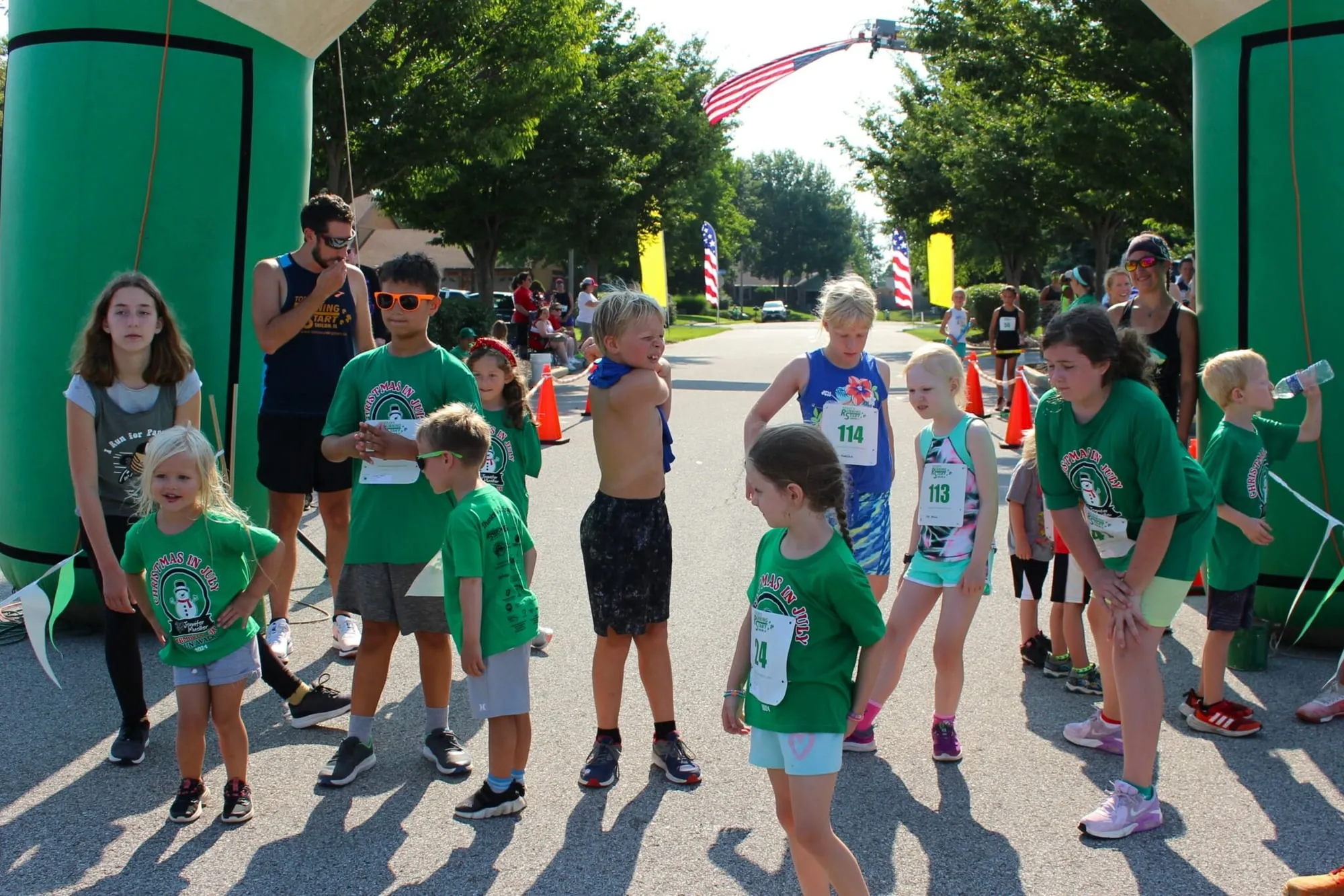 Dozens of children in green shirts running the Kids Fun Run.