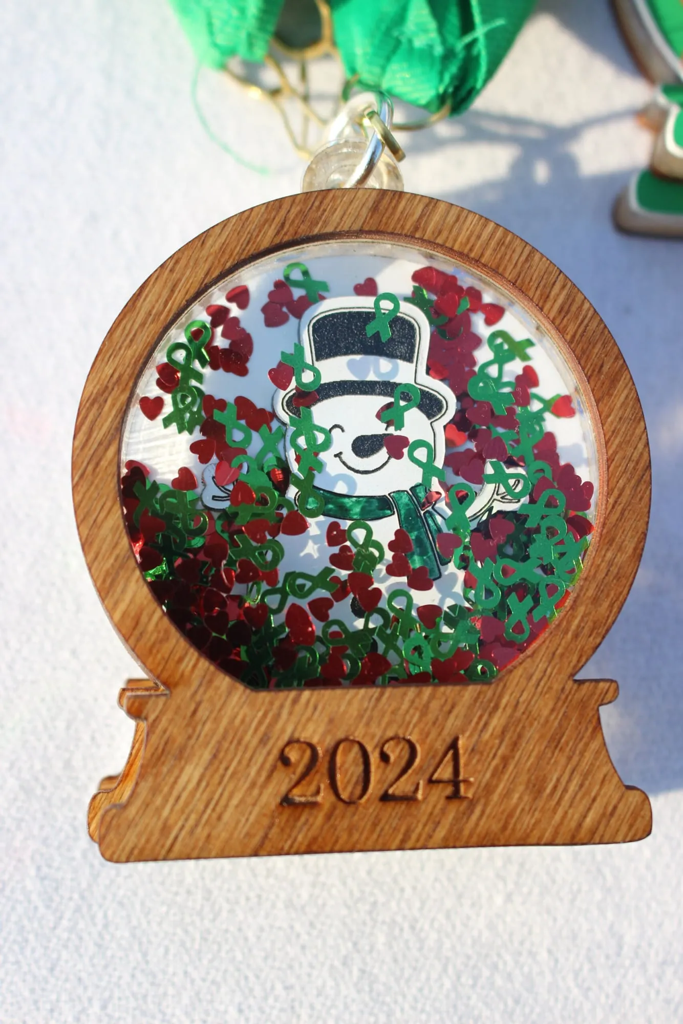 A close-up of the finisher medal: a hand-painted snowman inside a wooden hoop with a red and green wreath.