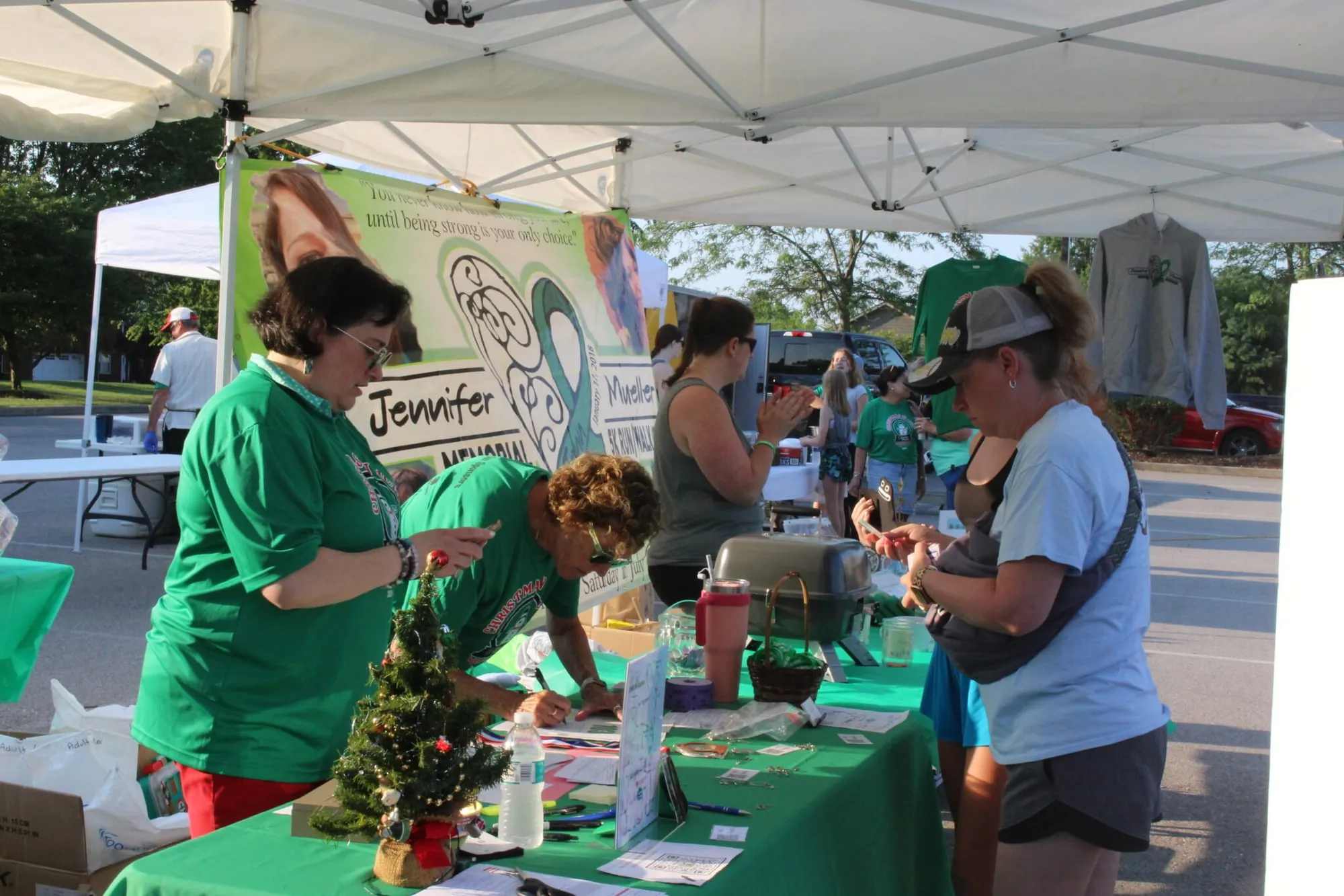 Volunteers in green shirts working the registration and merchandise tent under the foundation banner.