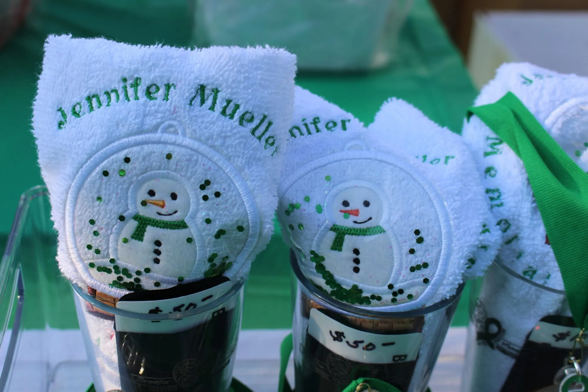 Two hand-painted snowman finisher ornaments resting on a Jennifer Mueller towel.
