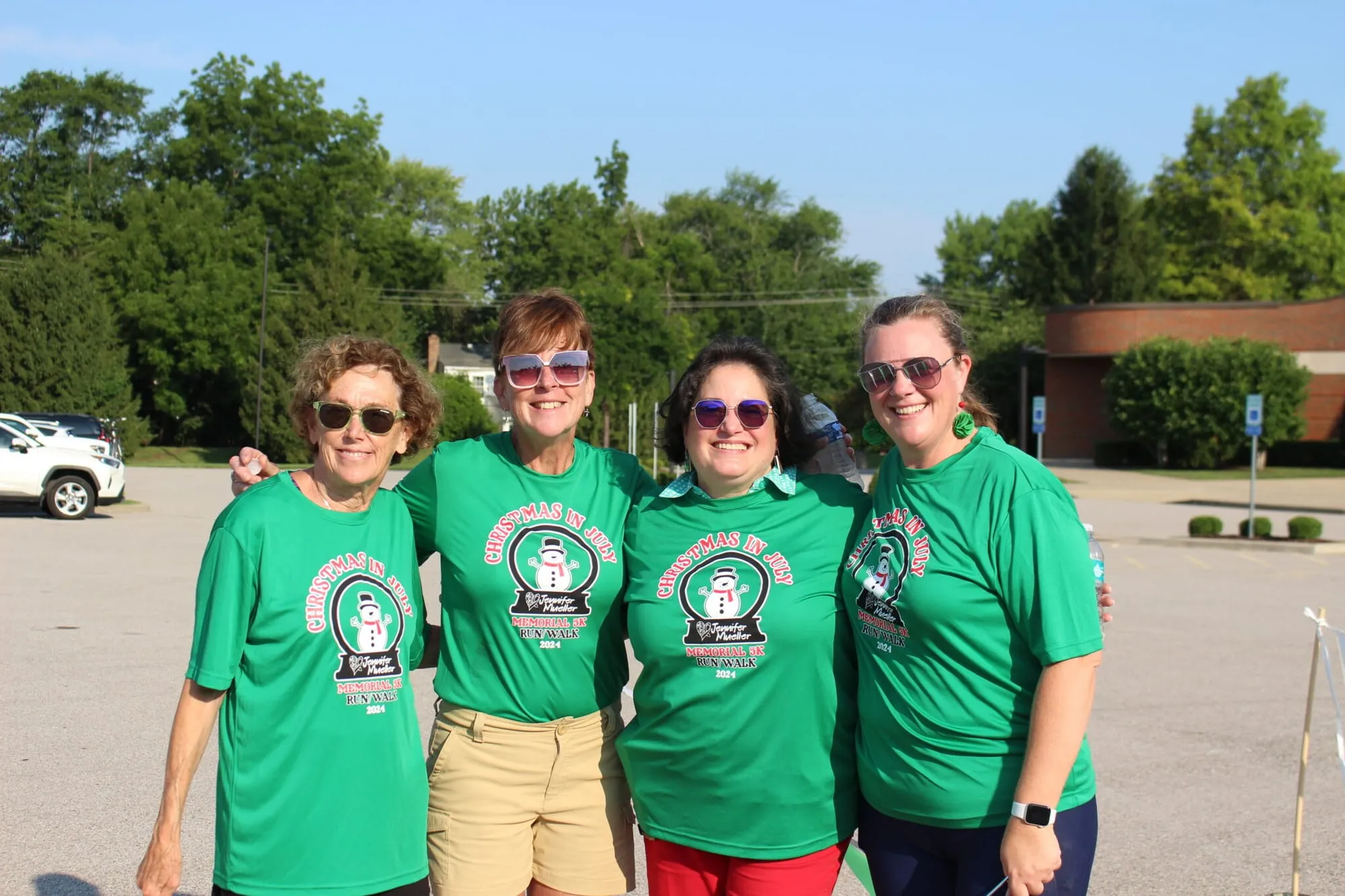 Four volunteers in matching green foundation shirts standing together in a parking lot.