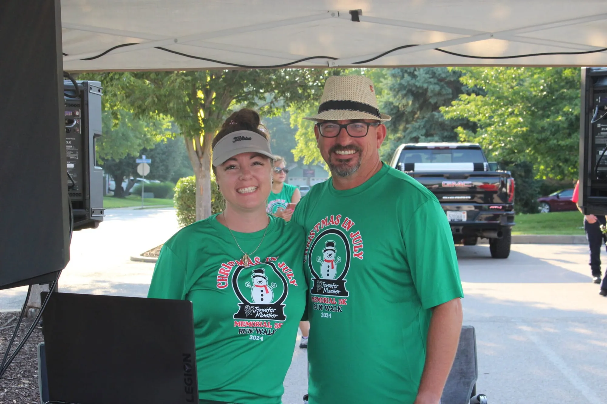 Two volunteers in green shirts working together under the race tent.